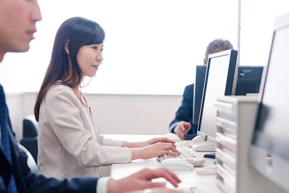 オフィスで並んでパソコン作業をする社員