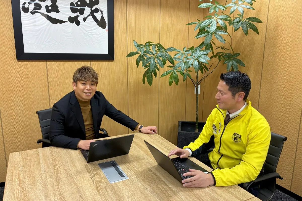2人の社員がノートパソコンを操作しながら机で面談している風景