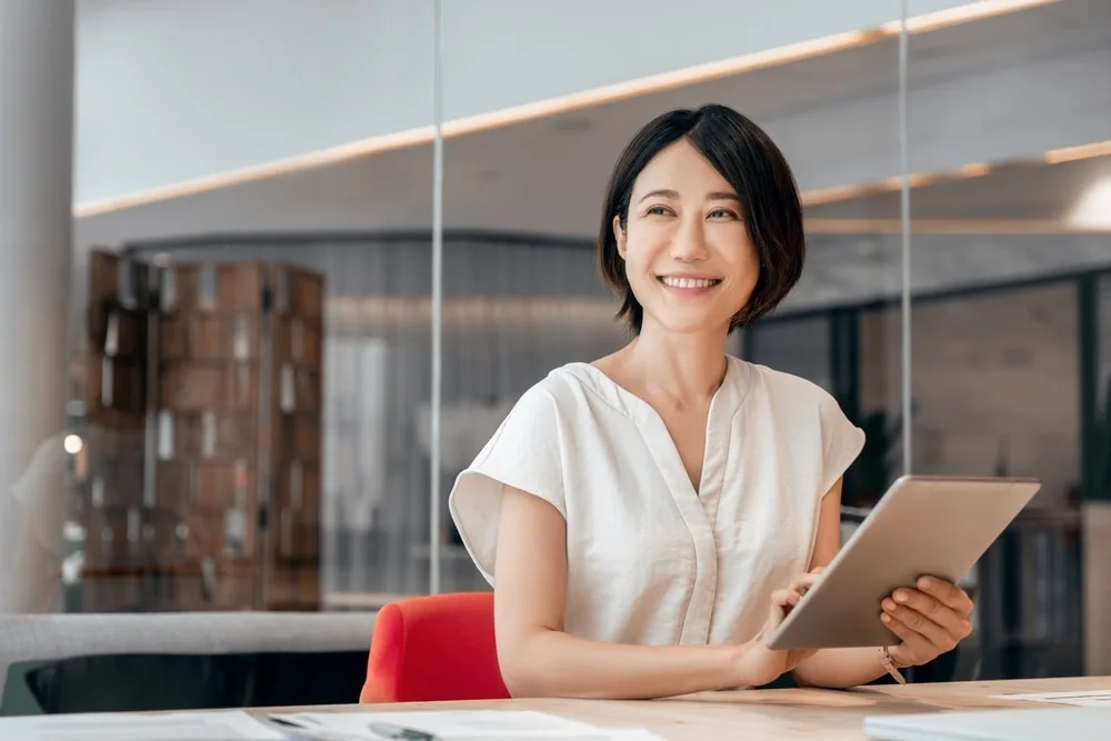 タブレットを持ってデスクに座る女性営業職