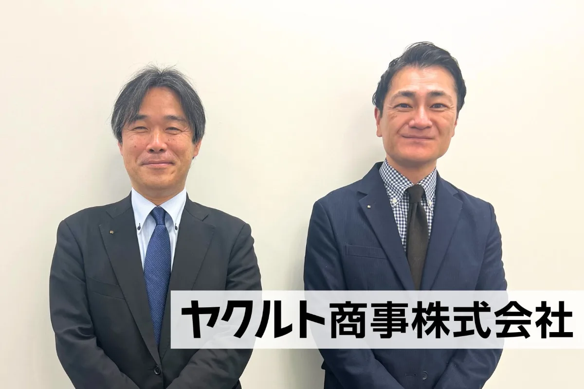 ヤクルト商事の社員複数人が白い背景の前で並ぶ