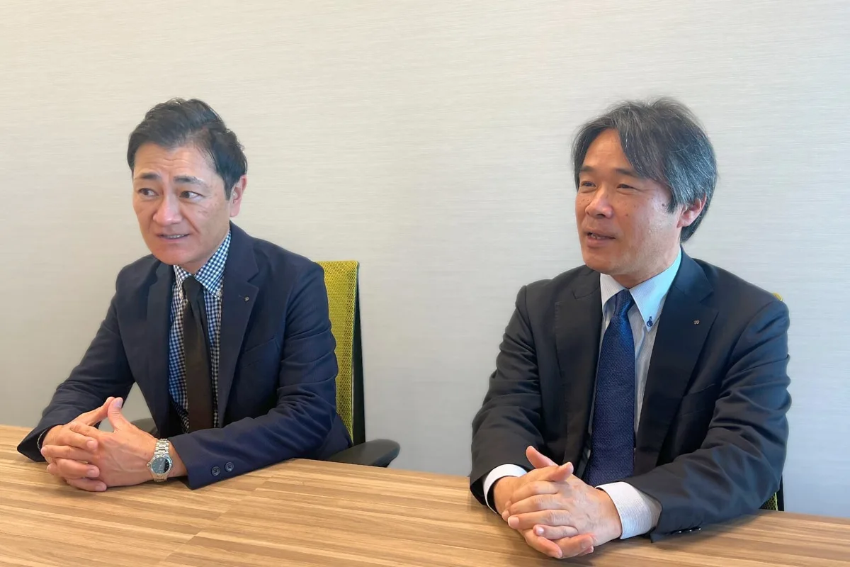 ビジネススーツの男性2名がテーブルを前に対談している様子