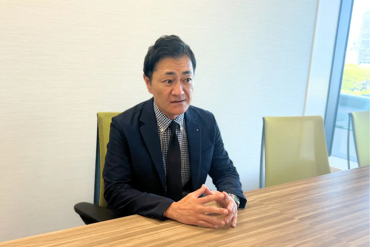 オフィスのテーブルに座りインタビューに応じる男性