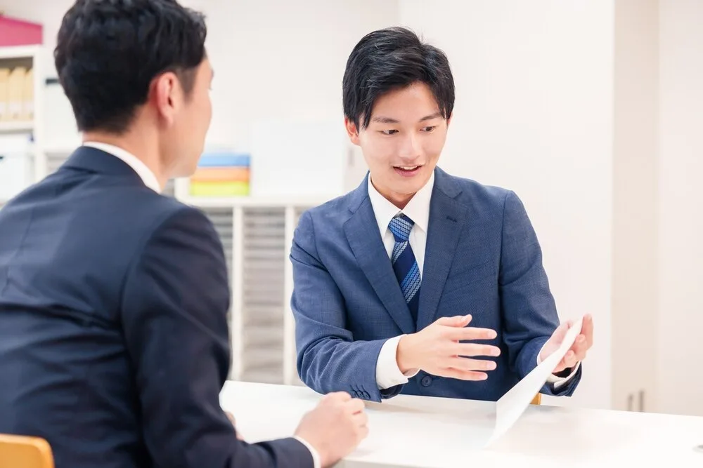営業担当者が顧客に提案資料を説明している。
