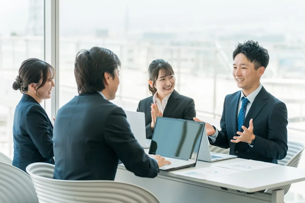 窓際の会議室でノートパソコンを囲む四人