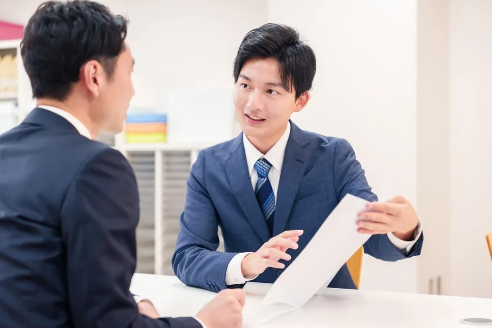 資料を手に説明する営業担当者と話を聞く男性