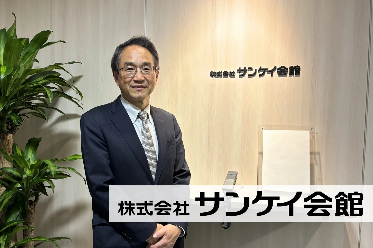 スーツ姿の男性がサンケイ会館のエントランスで立つ