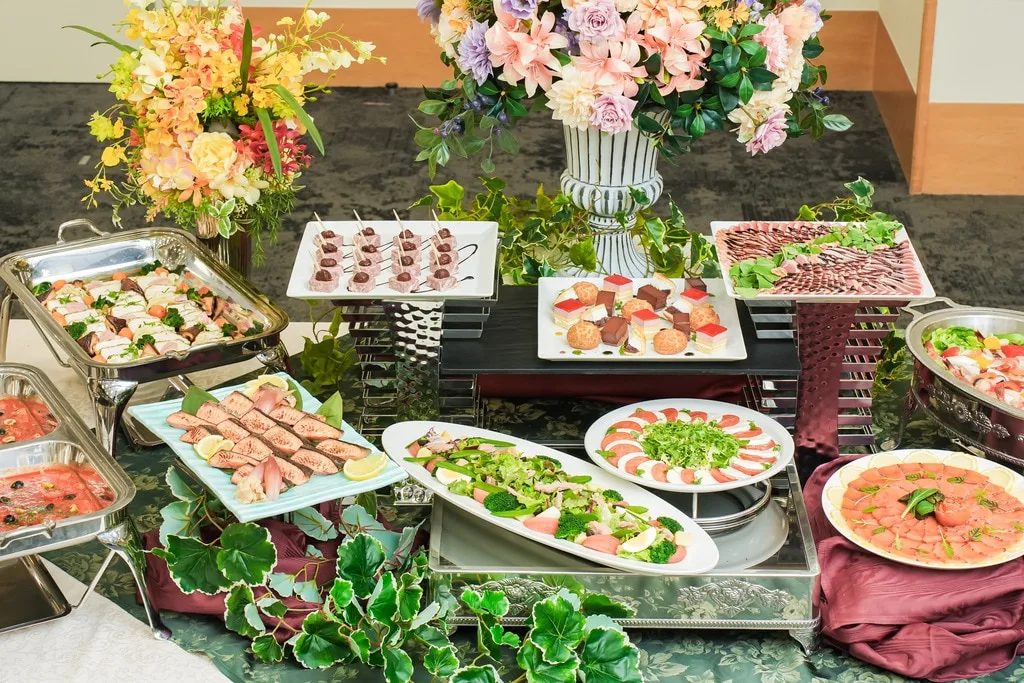 花飾りに囲まれたケータリング料理のテーブル